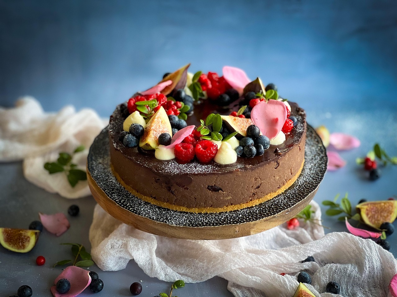 A chocolate cake with smooth frosting, topped with fresh raspberries, blueberries, and blackberries.